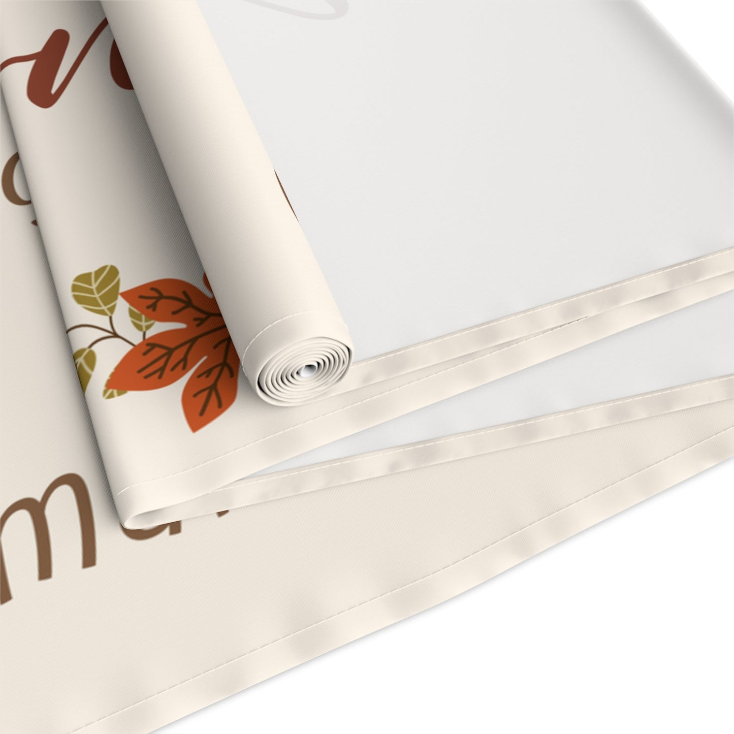 Roll of table runner with autumn leaf design on a white background