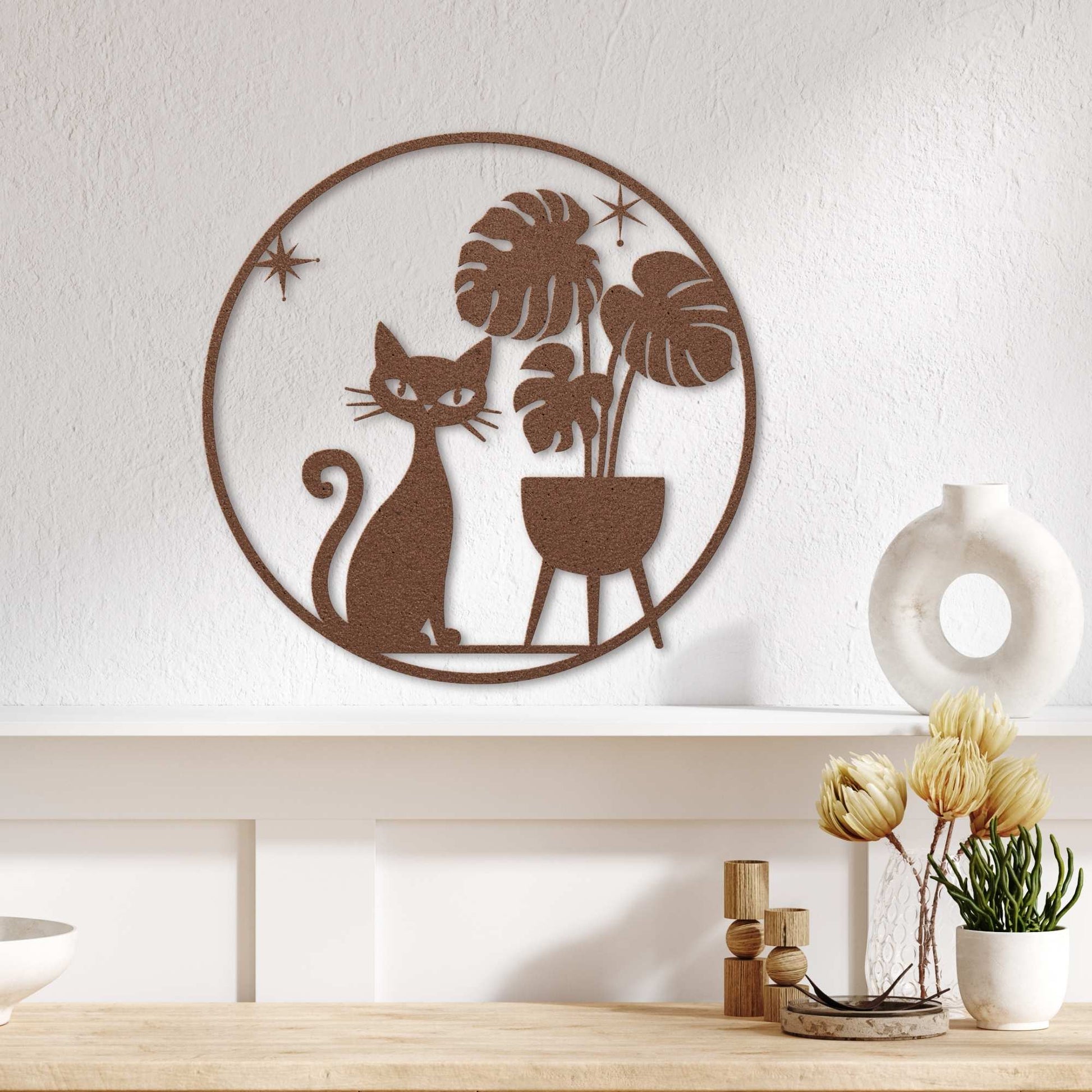 Decorative wall art of a cat and plants on a white wall above a wooden surface with decor items.