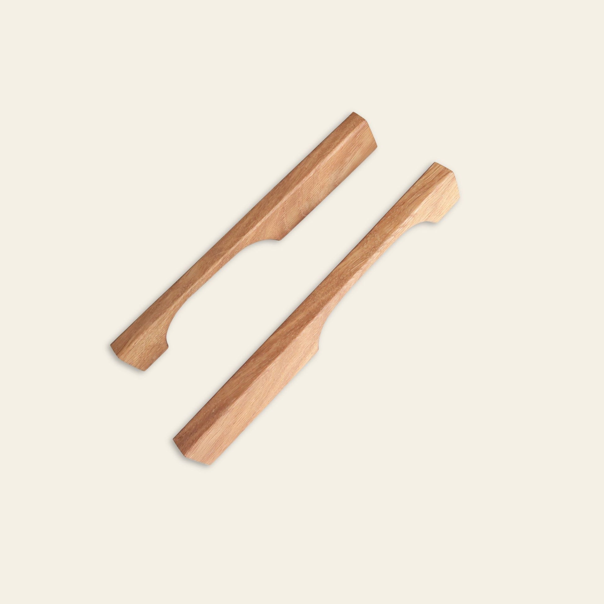 Pair of angular oak wood handles with minimalist cut design on neutral background