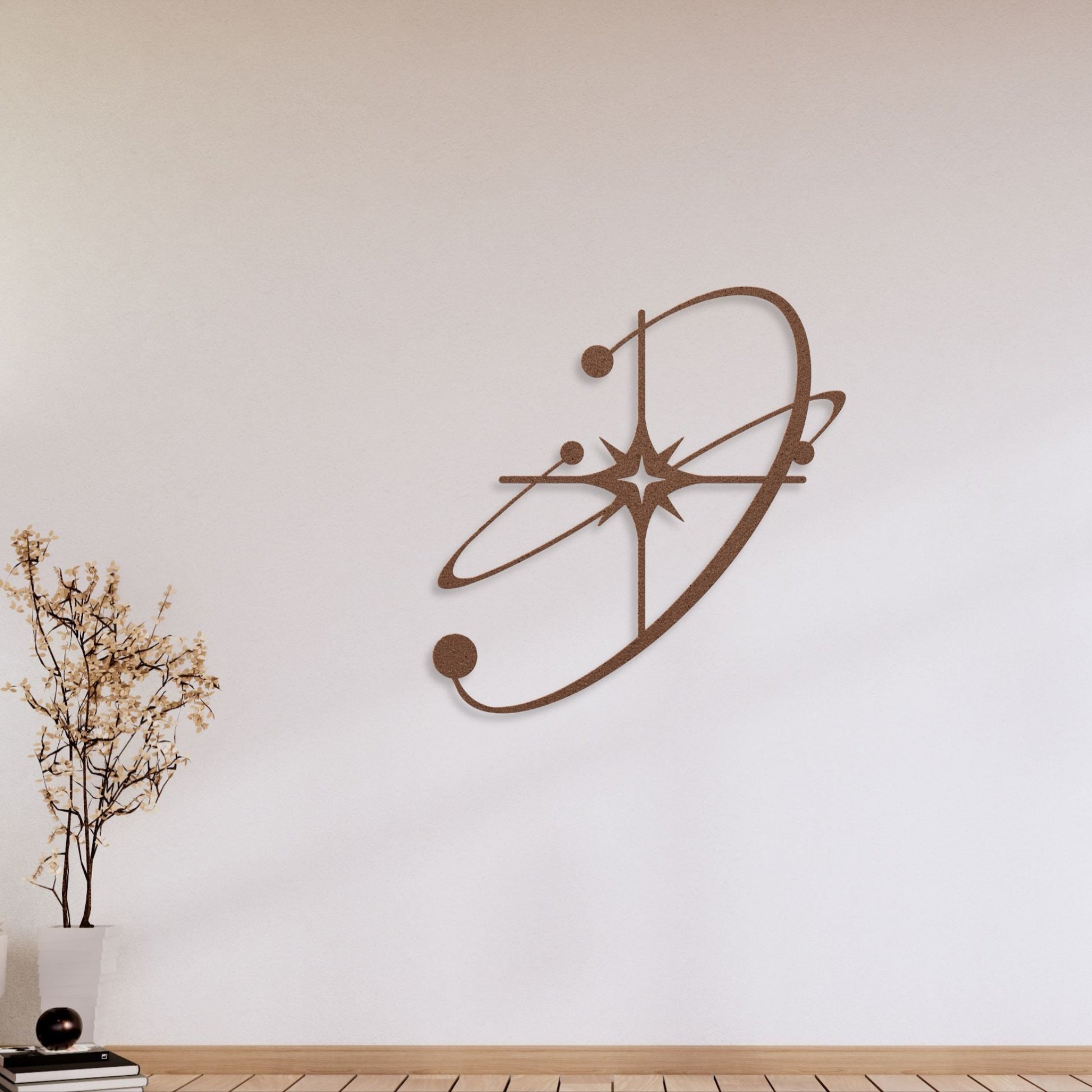 Decorative atomic wall art on a plain wall with a plant and books on a wooden surface.