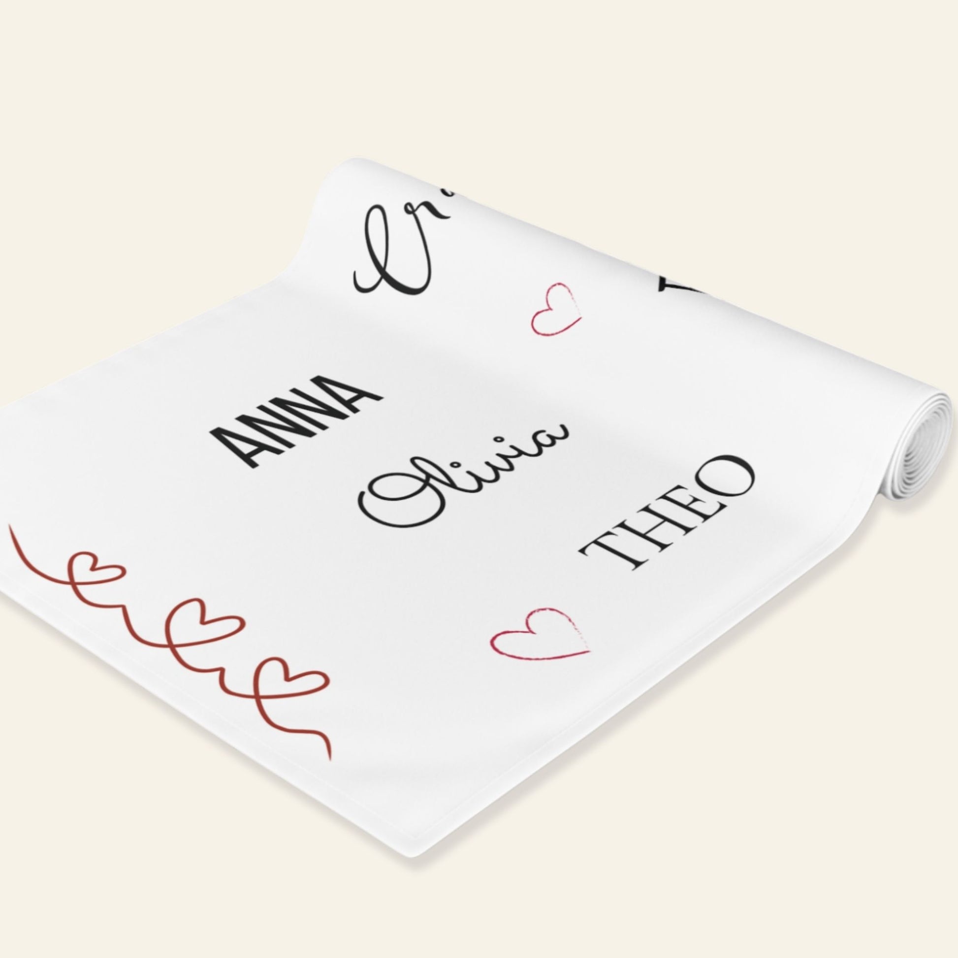 Personalized name labels on a white roll of table runner with decorative hearts.
