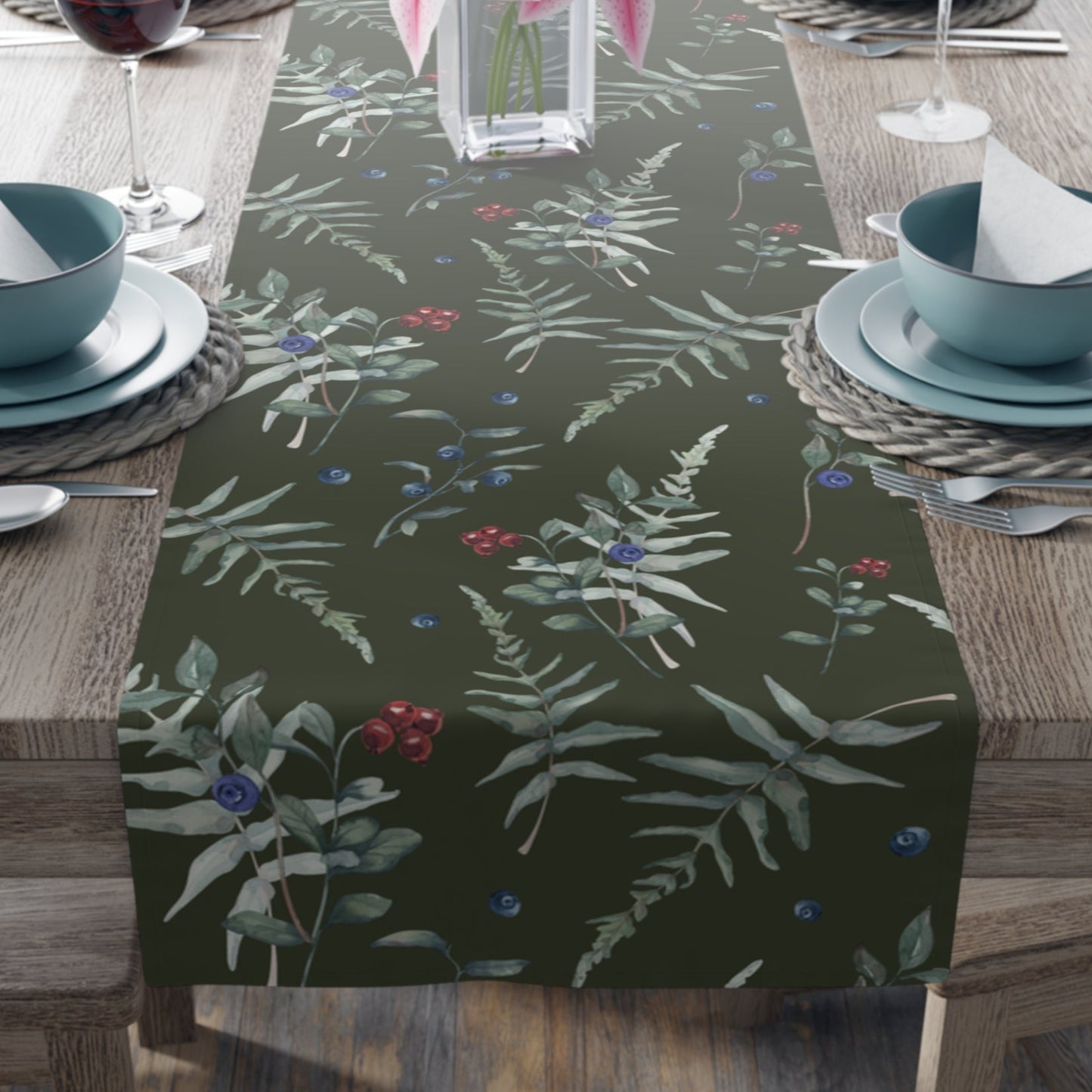 The table runner has a dark green background with a pattern of green leaves, red  and blue berries