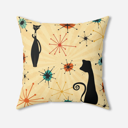 Pillow with a mid-century modern look, displaying black atomic cats  and atomic stars in yellow, teal and orange against a light yellow backdrop.