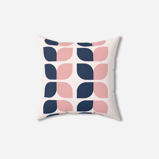 A throw pillow featuring a modern geometric pattern of pink and navy blue shapes on a white background.