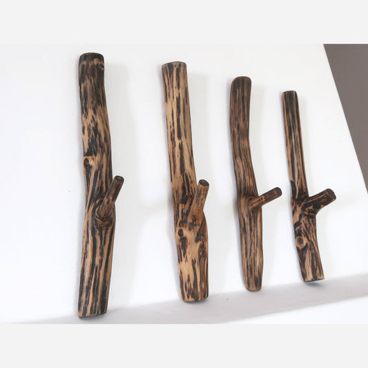 Four rustic oak wood wall hooks with a natural finish, mounted on a white wall, each with a unique branch-like design