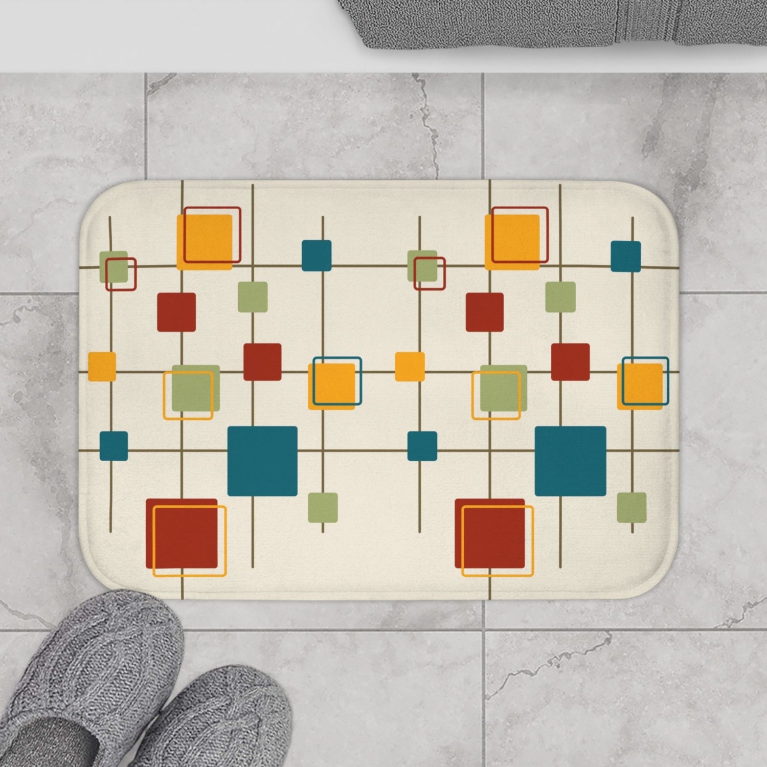 Bathroom mat with a colorful geometric pattern of red, orange, blue, and green squares, placed on a gray tiled floor