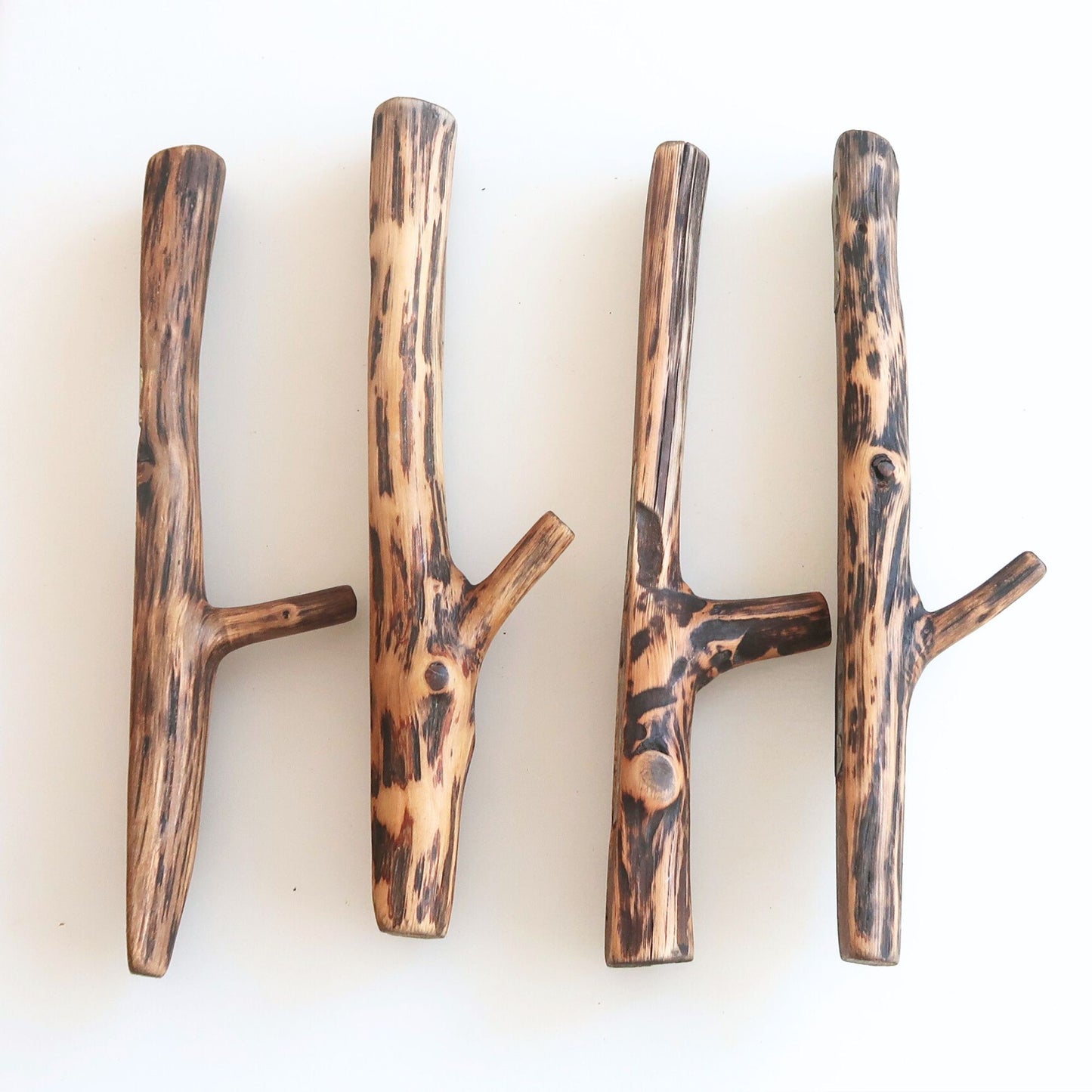 Four wooden hooks with brown oak branch on a white background