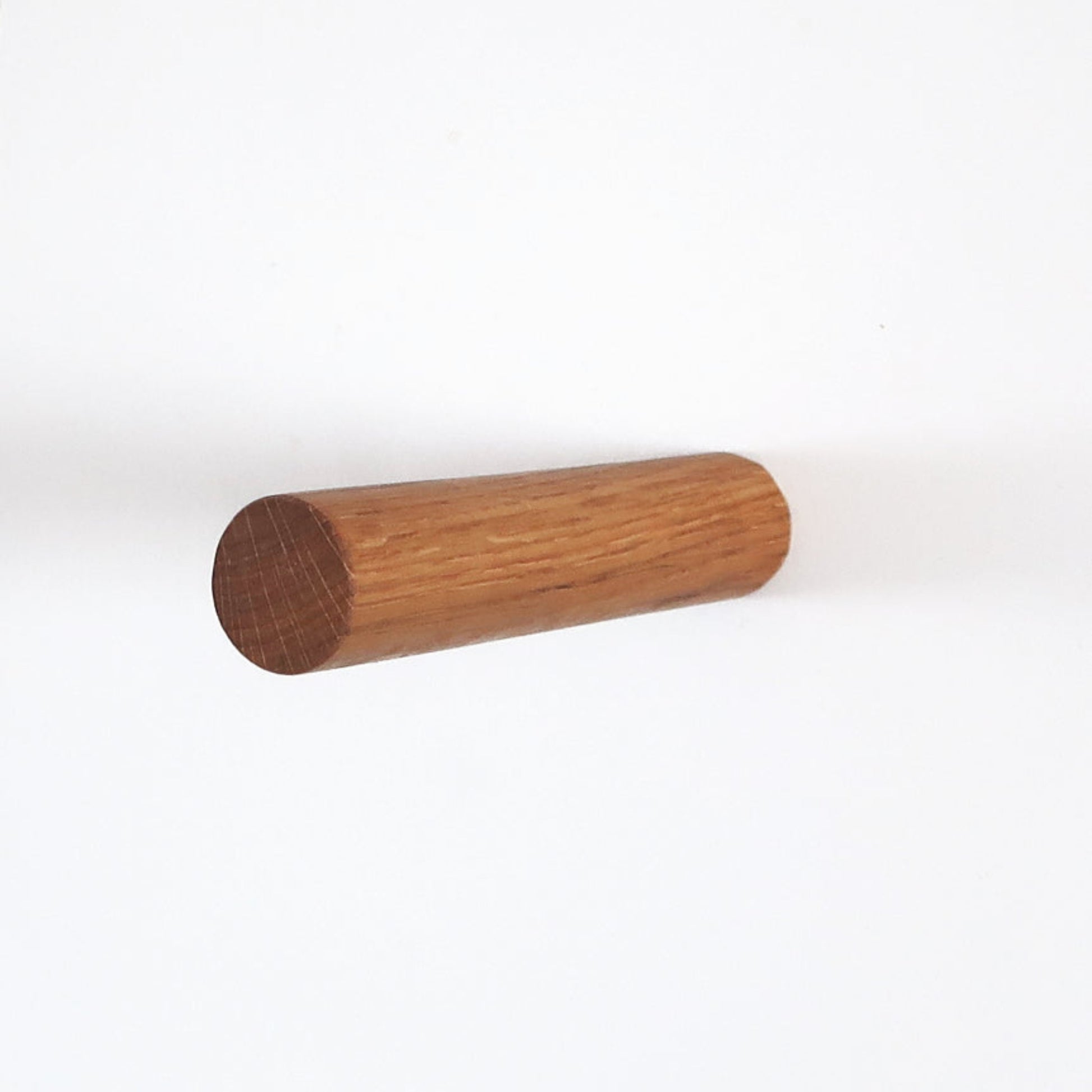 Minimalist wall hook made of solid oak wood, cylindrical shape, front view on white background.