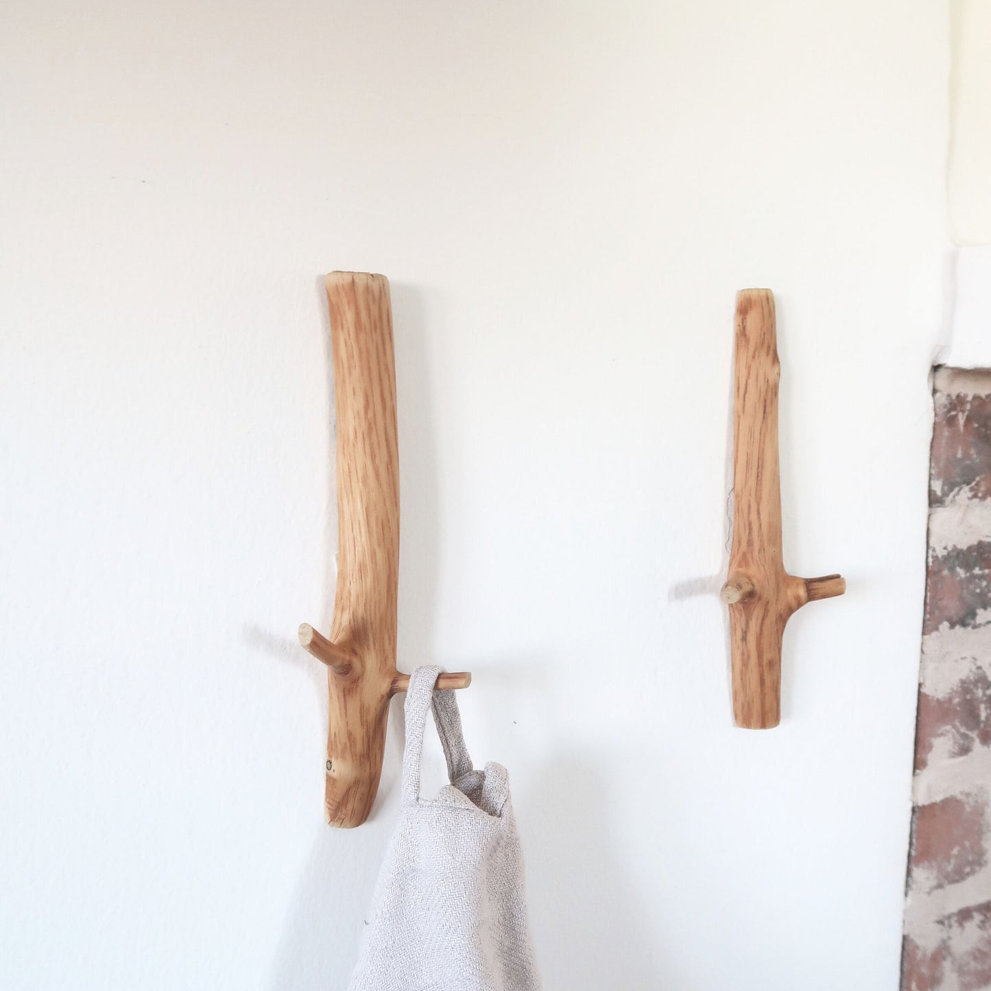 Two oak wall hooks on a white wall 