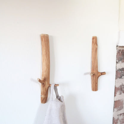Two oak wall hooks on a white wall 