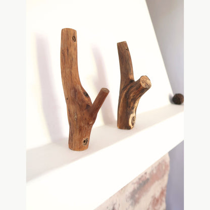 Two wooden branch hooks on a white surface