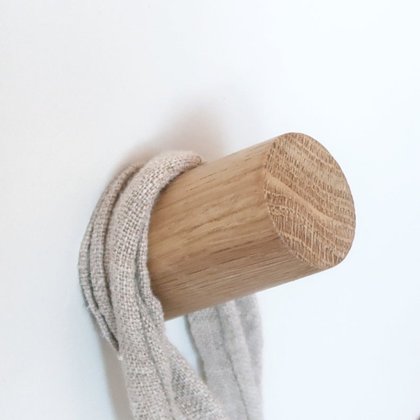 Small oak wall hook holding a linen strap