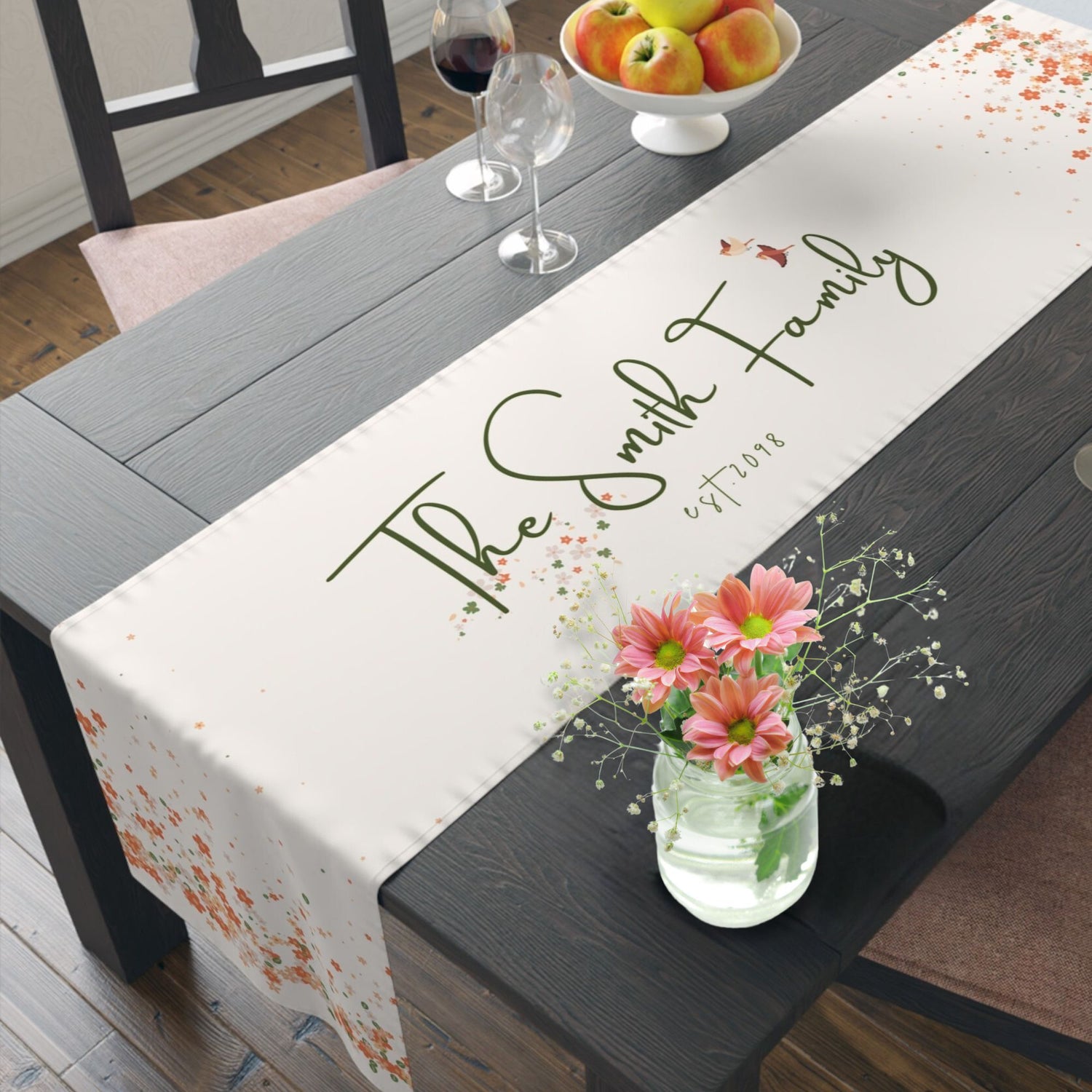 	Elegant floral table runner with soft pink cherry blossoms on a dining table.