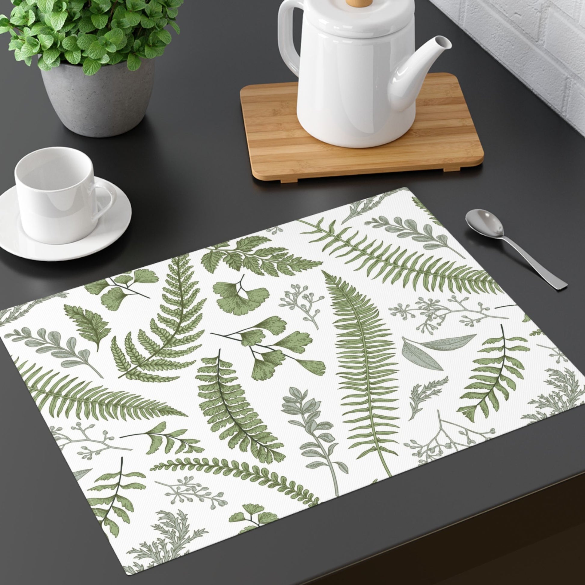 A white placemat shown exposing a green botanical print featuring different fern leaves.