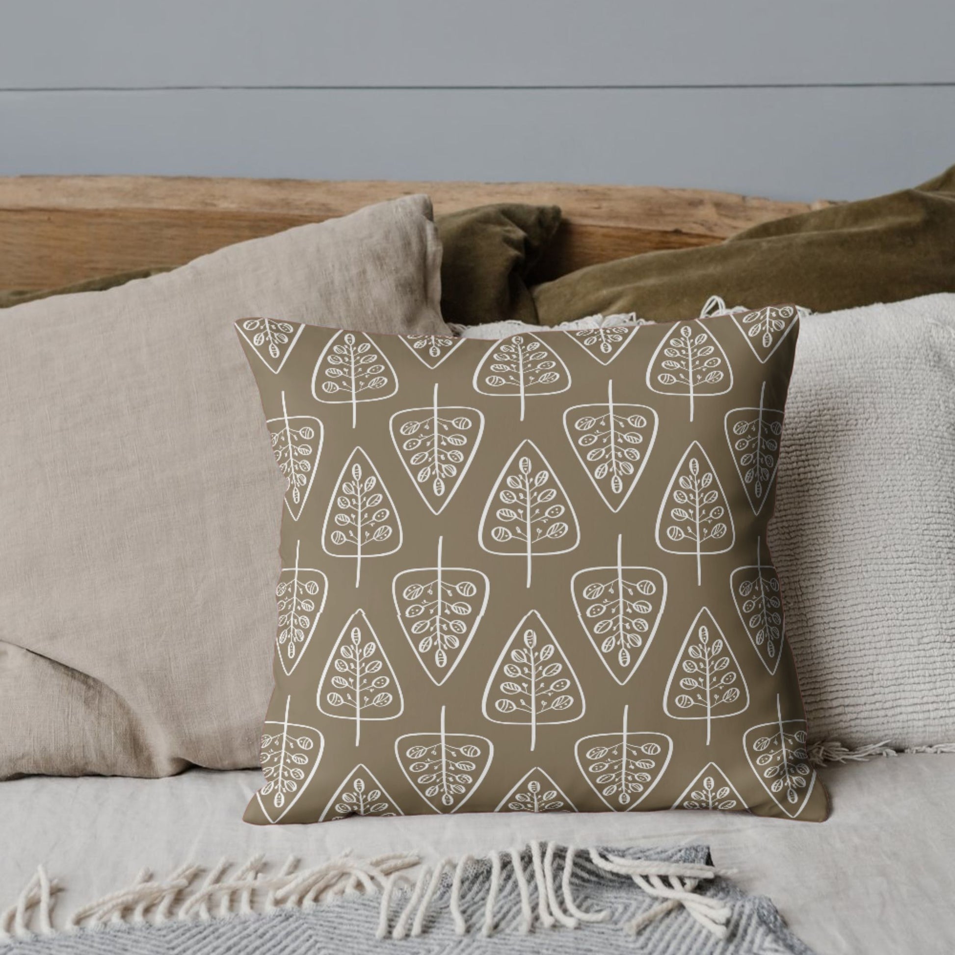 A throw pillow with a brown cover, adorned with a repeating pattern of white outlined trees, giving it a rustic and organic charm.