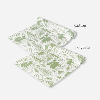 two white table runners patterned in green woodland motifs, including animals and trees.