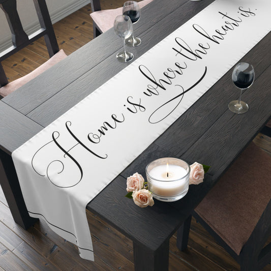 Elegant white table runner on a dark wood table, showcasing the phrase "Home is where the heart is" in cursive