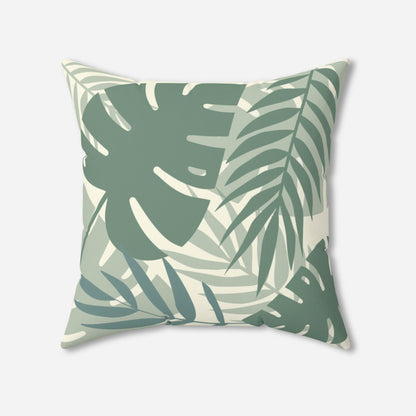 A square throw pillow with a tropical leaf pattern in shades of green and white. The design features large monstera and palm leaves, creating a fresh, botanical look.