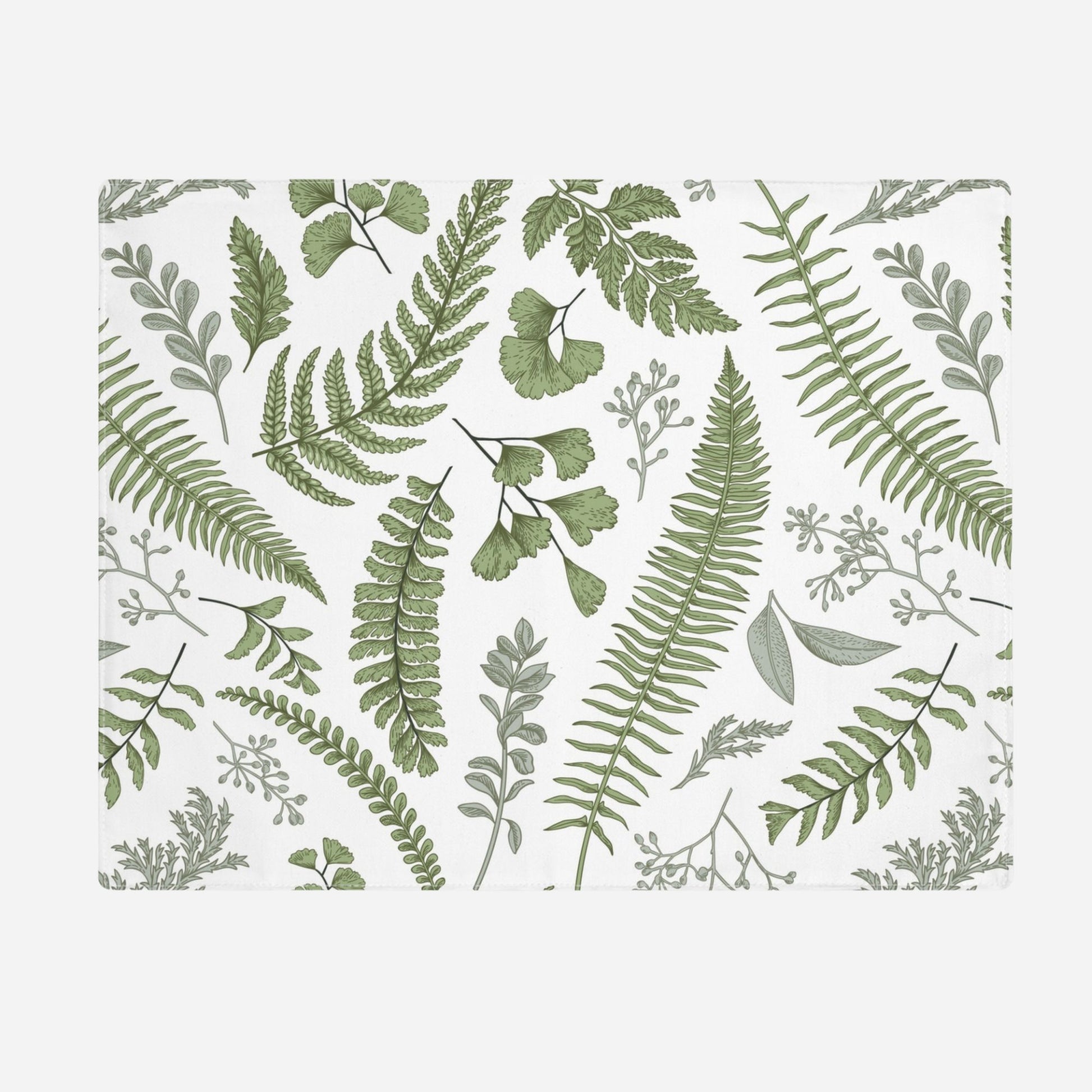 A white placemat with revealing a green botanical pattern featuring various ferns and leaves. The design includes delicate, detailed illustrations of different types of foliage on a white background.