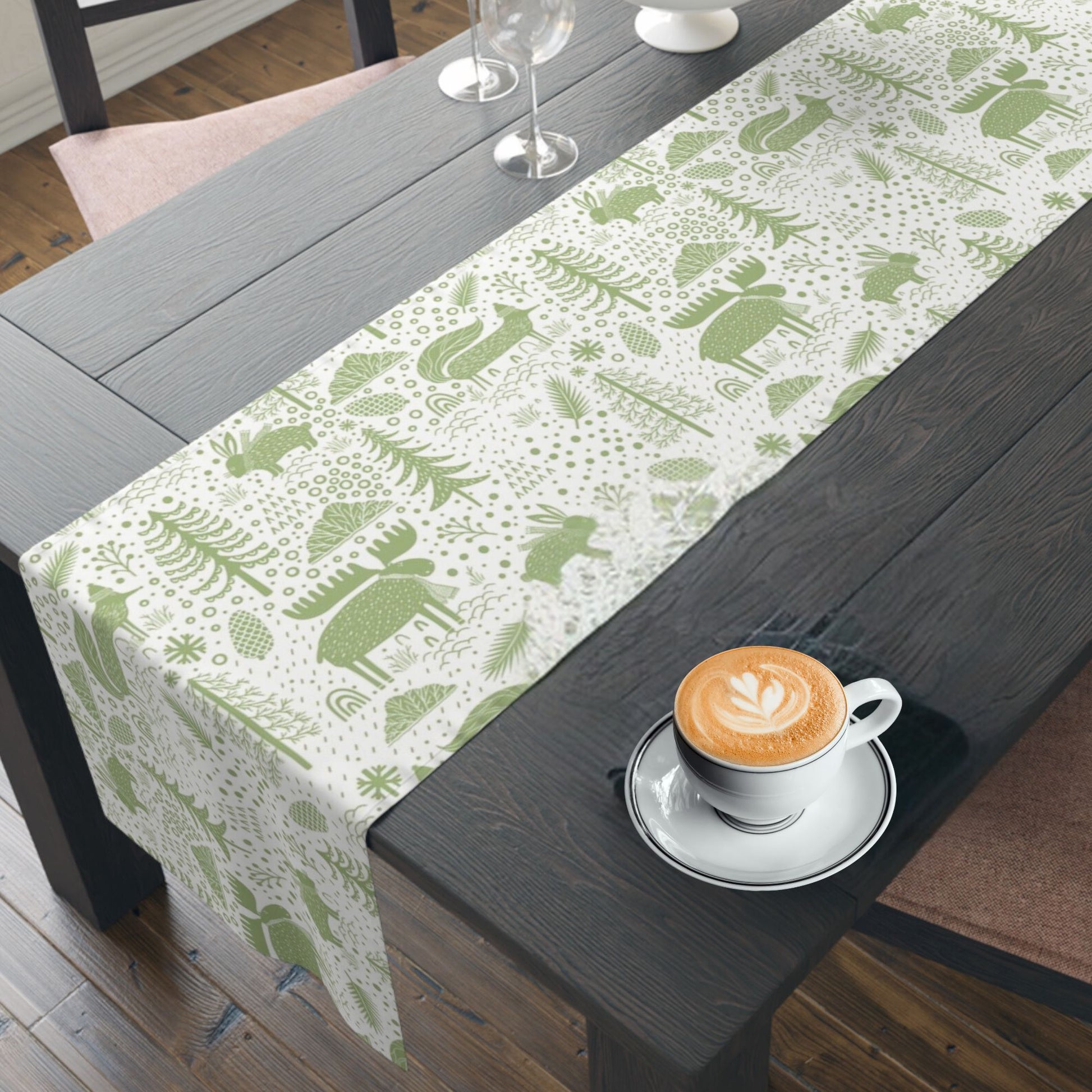 Dining table with a white and green table runner showcasing a festive design of animals and trees. 